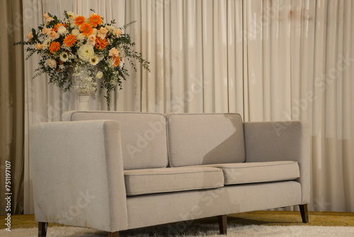 Sofa with Bouquets of colorful flower to decorated in the vase with curtain background in the living room.