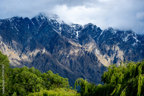 A moody rugged mountain range with clouds and green trees  photo