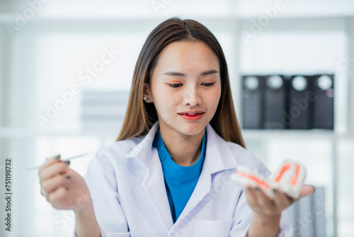 female dentist Denture model, tooth simulator and survey mirror tool for showing and explaining to patients at clinic office, dental health care concept.