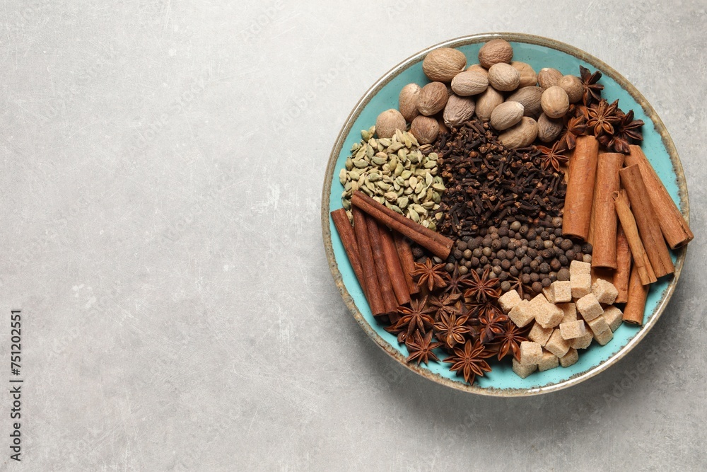 Different spices and nuts in bowl on light gray textured table, top view. Space for text Different spices and nuts in bowl on light gray textured table, top view. Space for text