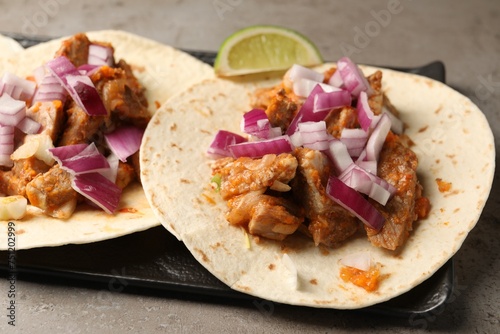 Delicious tacos with vegetables and meat on grey textured table, closeup