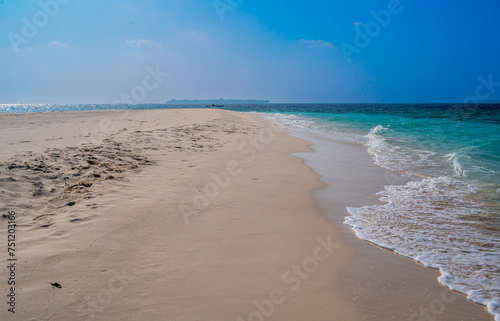Fototapeta Naklejka Na Ścianę i Meble -  Large sandy beach with a view of the ocean and an island on the horizon.