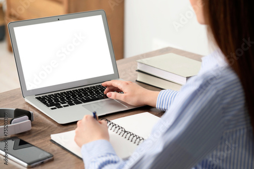E-learning. Woman taking notes during online lesson at table indoors, closeup