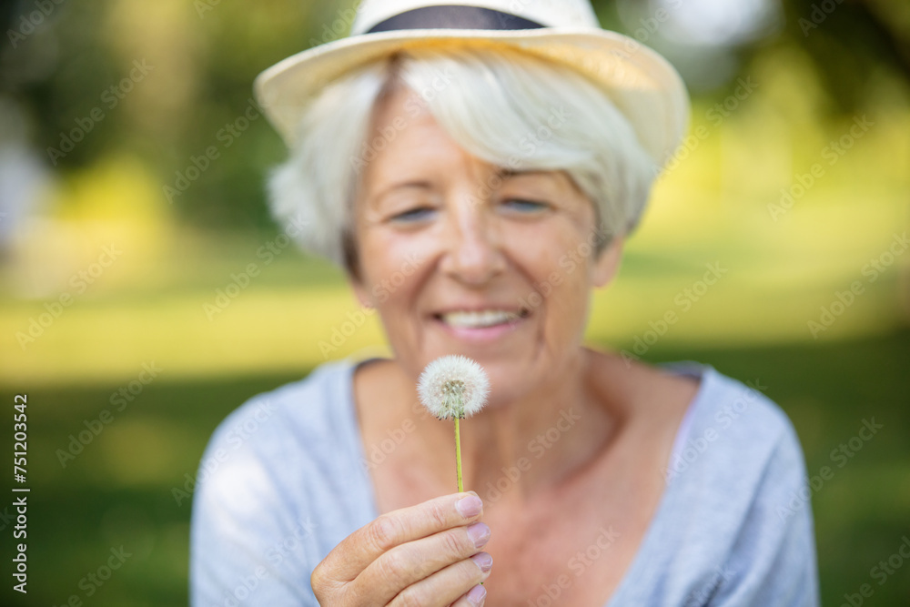 happy elderly woman senior blowing on a dandelion happy elderly woman senior blowing on a dandelion