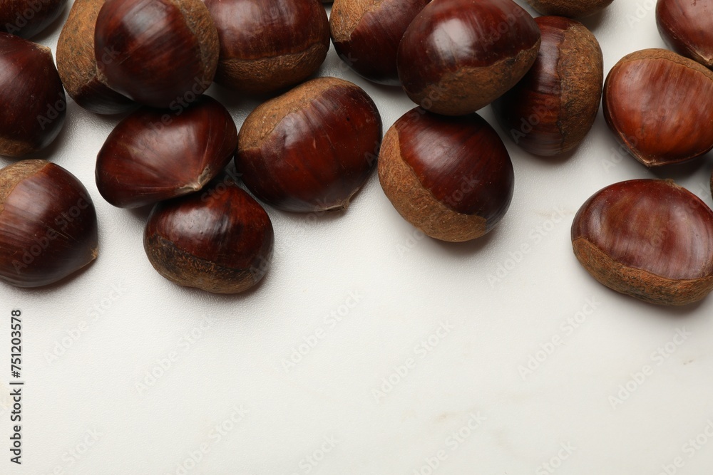 Sweet fresh edible chestnuts on white marble table, top view. Space for text Sweet fresh edible chestnuts on white marble table, top view. Space for text