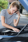 woman on the phone next to broken car engine