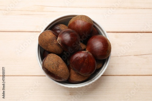 Sweet fresh edible chestnuts on light wooden table, top view
