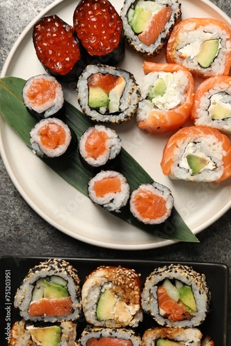 Delicious sushi rolls on grey table, flat lay