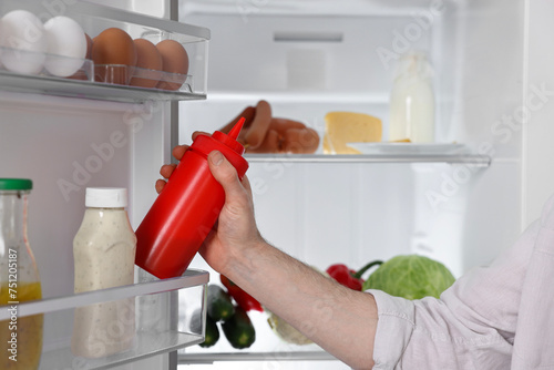 Man taking ketchup out of refrigerator, closeup
