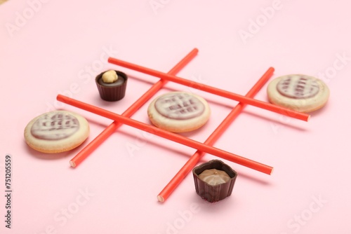 Tic tac toe game made with cookies and sweets on pink background