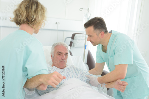nurses helping to raise patient up in hospital bed
