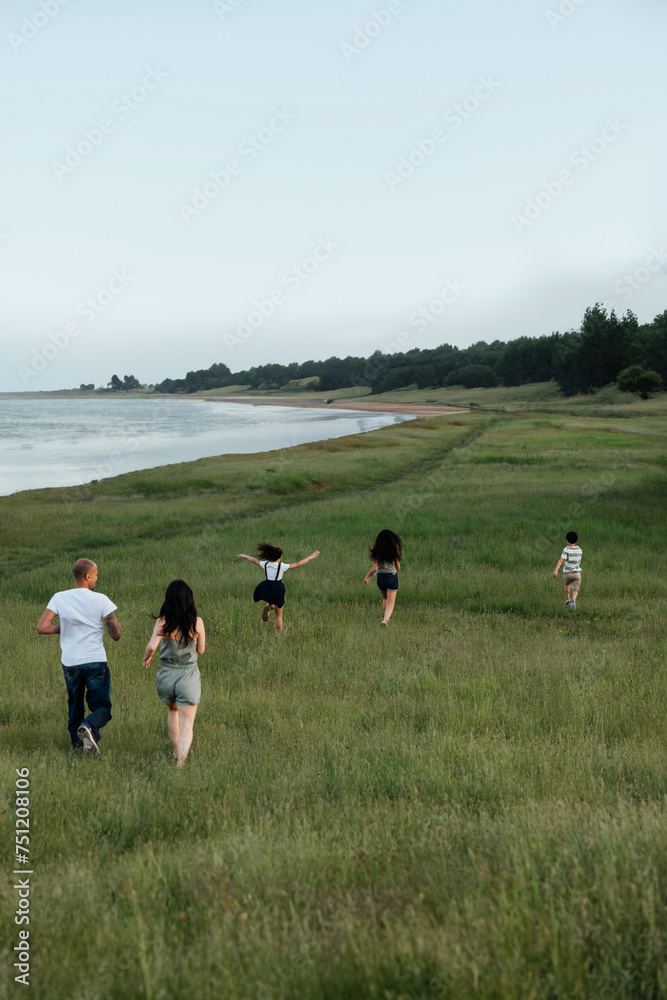 Playful family running through grass together. Playful family running through grass together.