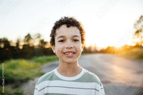 Portrait of cute curly haired boy having fun outside. photo