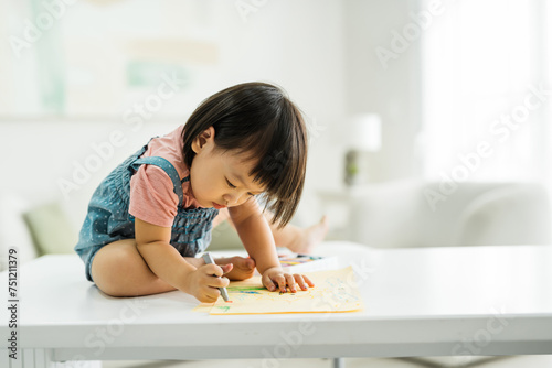 Cute little toddler girl drawing with crayons colour on the notebook photo