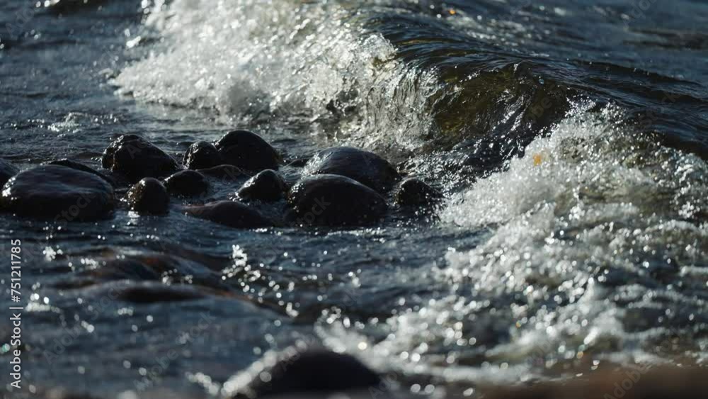 Waves roll and crush onto the pebble beach and rise water spray into the air. Waves roll and crush onto the pebble beach and rise water spray into the air.