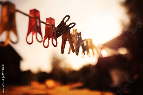 One old retro clothespin wooden on a linen rope. Work on the house, washing, drying linen. Abstract yellow orange autumn background. Concept of outdated forgotten things photo