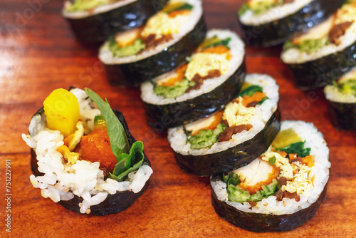Korean kimbab rolls with vegetables and chicken on board, top view.