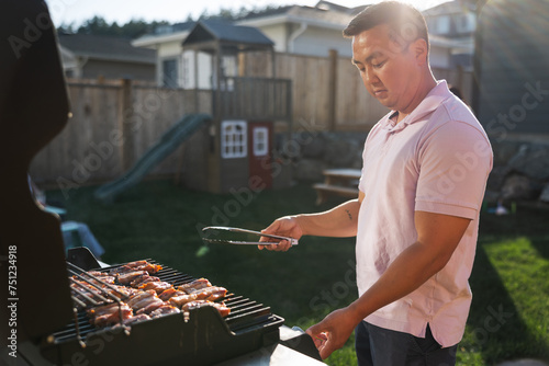 Content man enjoying grilling on his backyard BBQ in the sunshin photo