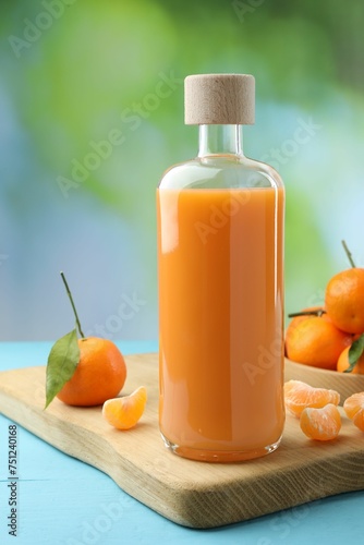 Fototapeta Naklejka Na Ścianę i Meble -  Delicious tangerine liqueur and fresh fruits on light blue wooden table