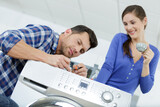 woman looking at repairman repairing dishwasher in kitchen