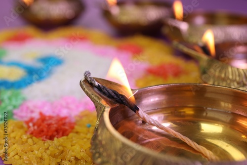 Diwali celebration. Diya lamps and colorful rangoli on blurred background  closeup