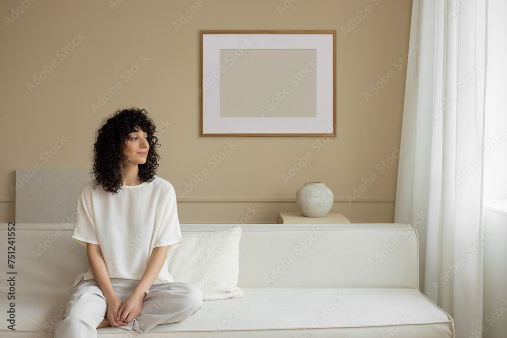 Stylish young woman and mockup frame in designer interior Stylish young woman and mockup frame in designer interior