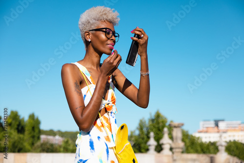 Black woman applying makeup in the street photo