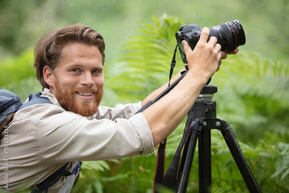 man photographer hand holding dslr camera next to trees