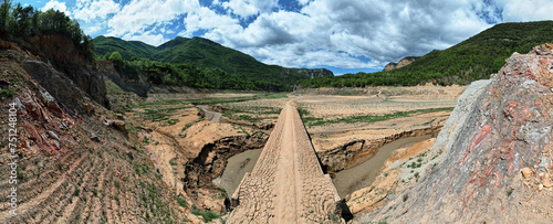 Dirt road bridge reappears from dry dam reservoir in drought photo