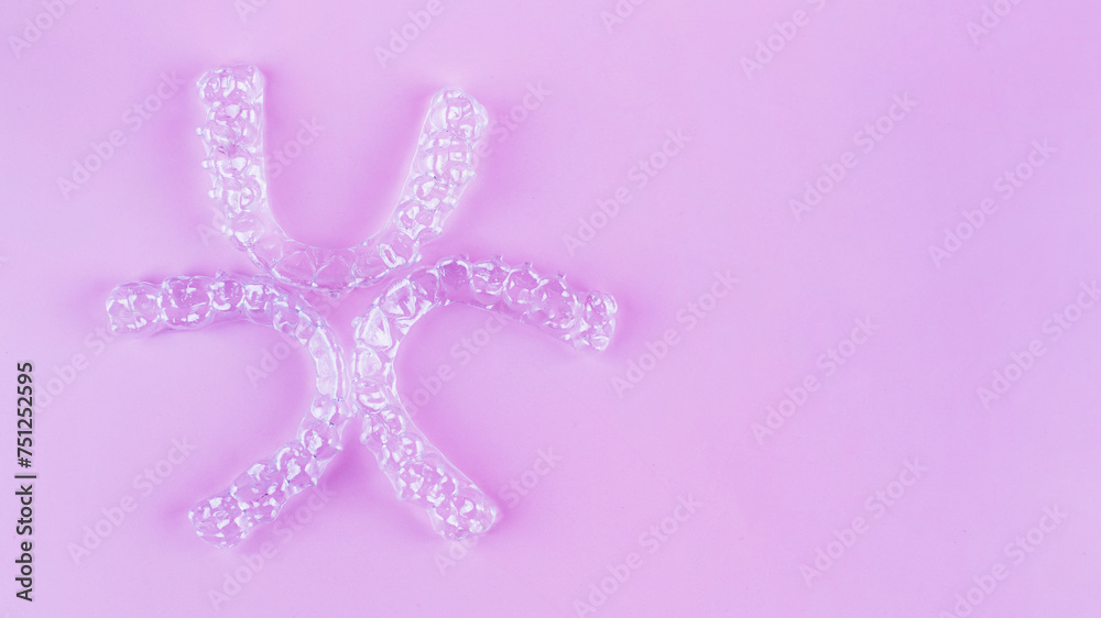 Invisible dental teeth brackets tooth aligners on pink background. Plastic braces dentistry retainers to straighten teeth. Invisible dental teeth brackets tooth aligners on pink background. Plastic braces dentistry retainers to straighten teeth.