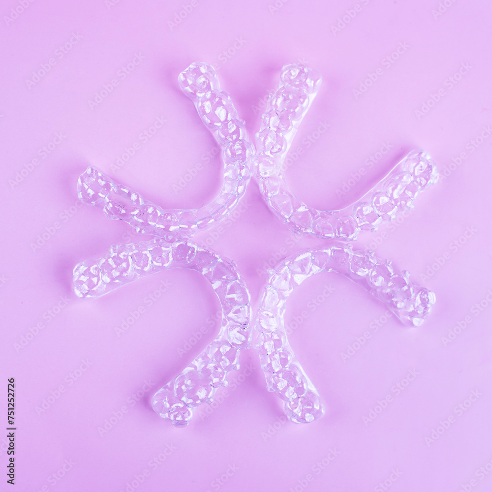 Invisible dental teeth brackets tooth aligners on pink background. Plastic braces dentistry retainers to straighten teeth. Invisible dental teeth brackets tooth aligners on pink background. Plastic braces dentistry retainers to straighten teeth.