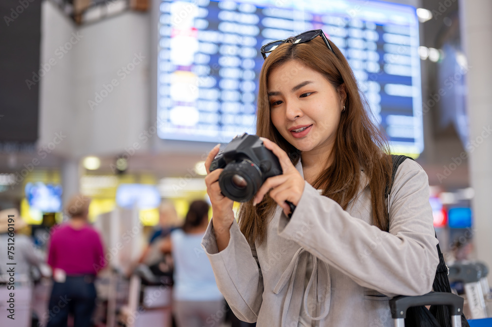 A woman is checking pictures in her camera while walking in the airport, traveling abroad. A woman is checking pictures in her camera while walking in the airport, traveling abroad.