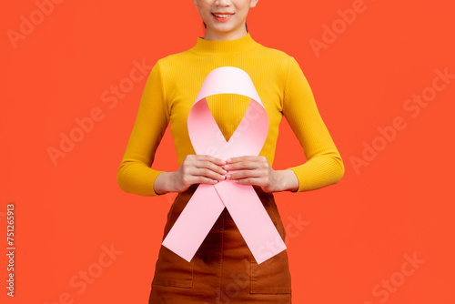 Woman in pink sweater with pink ribbon supporting breast photo