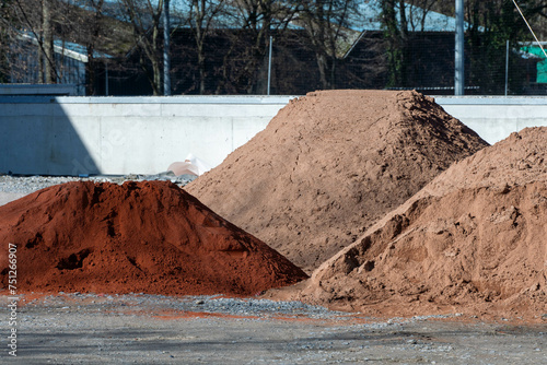 Excavated earth and sand mounds in various colours on a construction site for processing