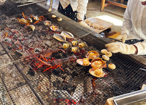 Obraz na płótnie 海女小屋で新鮮な伊勢海老や貝、魚を炭火焼きにする海女さん 三重県日本