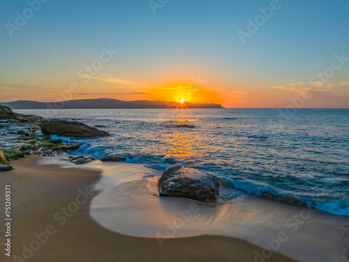 Aerial sunrise at the seaside with light scattered high cloud and a low cloud bank