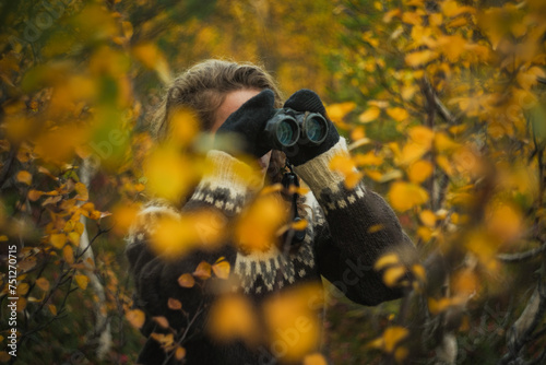 Caucasian woman birdwatching with binoculars autumn forest photo