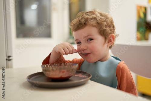 Young Boy Eating A Vegetable Puree Soup For Lunch At Home. photo