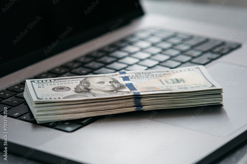 A stack of money on a laptop computer keyboard. Concept of financial savings, banking services, making money online and deposit. A stack of money on a laptop computer keyboard. Concept of financial savings, banking services, making money online and deposit.