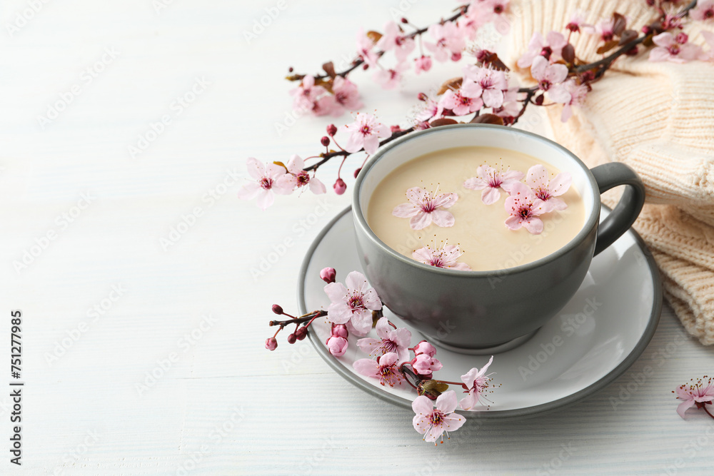 Spring twigs with flowers with a cup of hot drink, on a light wooden background. Spring twigs with flowers with a cup of hot drink, on a light wooden background.