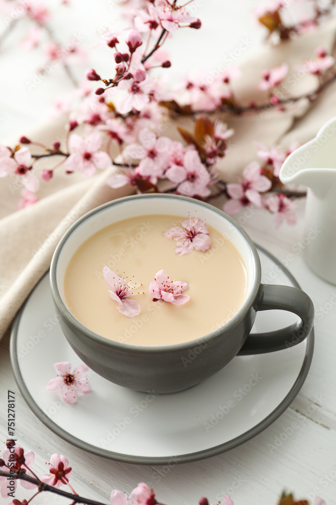 Spring twigs with flowers with a cup of hot drink, on a light wooden background. Spring twigs with flowers with a cup of hot drink, on a light wooden background.