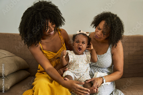 Baby is yawning while being cared for by her mother and grandmother photo