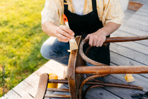 A man varnishes a chair outdoors