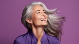 Joyful mature woman with silver hair, laughing, vibrant purple background, happy, carefree