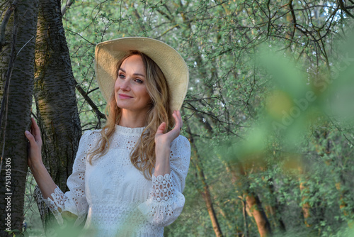 Wiosenny portret młodej ładnej kobiety w kapeluszu, w parku , wśród drzew.