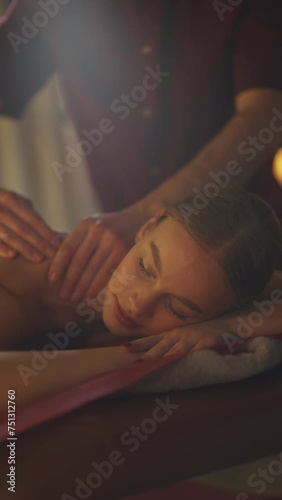 Professional masseur makes a relaxing legs massage to a young woman, using oils, female enjoy a massage, spa treatments, vertical video.