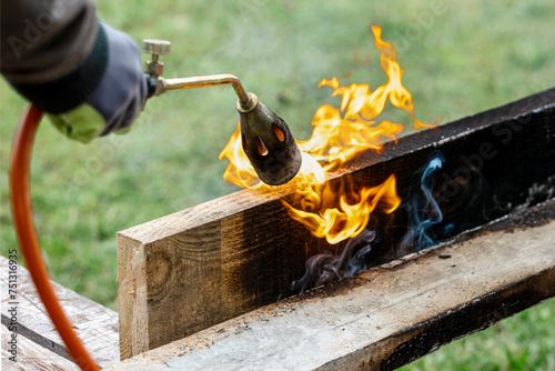 Burning Charring Wood Board with Fire Flame is way to Protect wood. Modern Preserve Wood for Using Outdoor.   photo