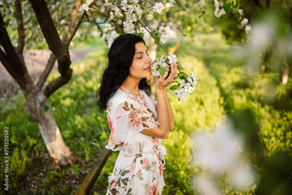 A young beautiful woman enjoys the smell of blooming trees in the spring garden. Rural landscape. Springtime. A young beautiful woman enjoys the smell of blooming trees in the spring garden. Rural landscape. Springtime.