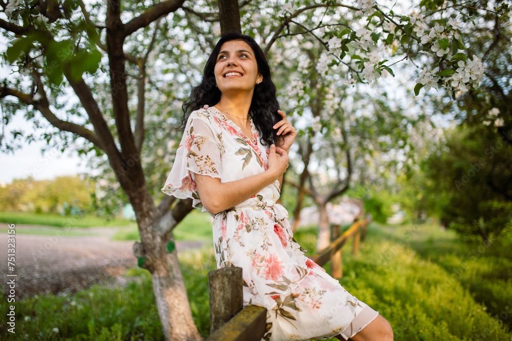 Vertical photo of a happy girl enjoying spring scenery. Woman in a blooming garden park. Rural landscape. Vertical photo of a happy girl enjoying spring scenery. Woman in a blooming garden park. Rural landscape.