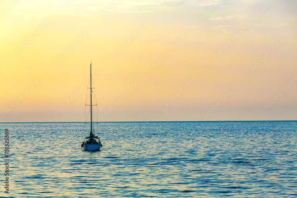 Serene seascape with a sailboat at dusk, basking in the gradient hues of the sunset across the calm sea
